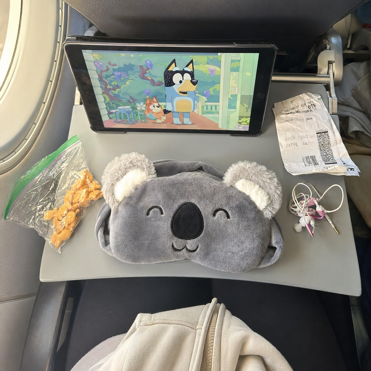 SleepBandy on airplane tray table with travel essentials